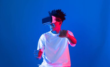 VR kullanan Afro-Amerikan oyun oyuncusu araba yarışı oyunu oynayan meta izole edilmiş mavi neon ışıklı arka duvar fütüristik teknoloji sanal gerçeklik yeni dünyayı birbirine bağlıyor. Entrika.