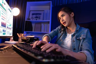 Genç ve güzel Asyalı yaratıcı kadın, gece modern ofisteki bilgisayar analizini ararken strateji pazarlama yaratıcısı planına bilgi vermek için müşteriyi ya da iş arkadaşını telefonla arıyor. Taktik.