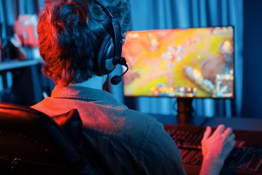 Savaş arenasında çoklu oyunlar takımıyla Moba 'da savaşan genç oyun flamasının sunucu kanalı, neon dijital ışık modern odasındaki arka görüntü ile bilgisayar monitöründe kulaklık takıyor. Toplayıcı.