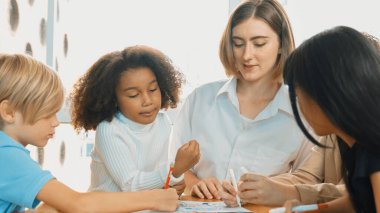 Masada masal kitabı ve renkli kitapla otururken çeşitli öğrencilere hikaye anlatan profesyonel beyaz bir öğretmen. Eğitmenden renkli resim alırken akıllı öğrenci dinlemeyi öğrenir. Etkinlik.
