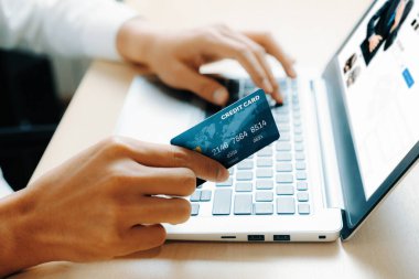 Genç adam, laptop bilgisayar başvurusu ya da web sitesinde online alışveriş yapmak için kredi kartı kullanıyor. E-ticaret ve online alışveriş konsepti. uds