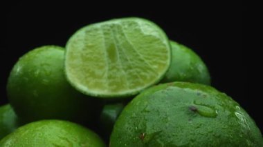 Limon dilimleri titizlikle bir yığın halinde, siyah arkaplana göre dizilmiş. Her bir kireç dilimi çarpıcı detaylar, canlı yeşil rengi ve baştan çıkarıcı dokusu ile yakalanır. Kapatın. Geliştirilebilir.