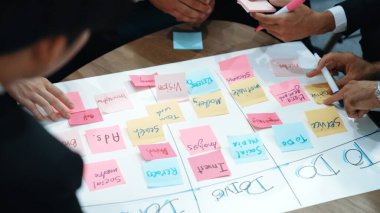 İş adamlarının işyerinde iş akışını yönetmek için sıkı yönetim kurulu kurması. Çeşitli pazarlama ekibi bir sınır çiziyor ve Kanban üzerinde çalışmak için renkli notlar kullanıyor. Kapatın. Müdürlük.