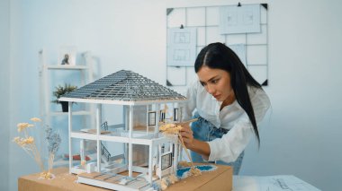 Genç, beyaz, güzel mimar mühendisi ev modelini ev inşaatını teftiş etmek ve sorunu modern ofisteki toplantı masasında çözmek için hata noktasını kontrol etmek üzere çeviriyor. - Yakın çekim. Tertemiz..