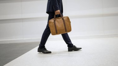 Profesyonel iş adamının bacağını tutarken yakın plan fotoğrafı. Proje yöneticisinin bacağa odaklanmış görüntüsü. Seyahat, taşınma, yolculuk, yürüyüş, yeni bir pozisyon alma, iş değiştirme. Sevinçli..