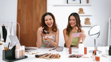 Etkilenen iki ortak canlı yayın yapan video görüntülerini sosyal medya ya da blog üzerinden gözden geçirir. Canlı kozmetik stüdyosu ışıklandırması olan mutlu genç bir kız pazarlama için internet üzerinden yayın yapıyor..