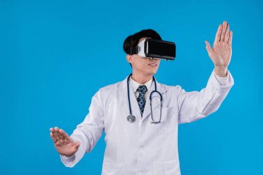 Sanal ortamda görüntü kaydedici kulaklıklı zeki bir doktor. Sağlık hizmetleri yenilik arayüzü 3 boyutlu hologram ekranı için sağIık teknolojisi konseptiyle mavi arka plan stüdyo portresi. Entrika.