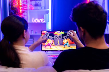 Televizyondaki çift ya da arkadaş canlısı video oyunu joystickleri kullanarak arka planda bir araya getiriyor. Bulanık ekranlı, neon siber ışıklı bir stüdyoda, rahat bir evde kazanan. Varsayım.