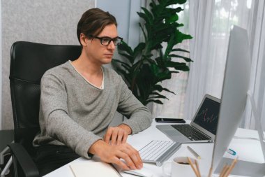 Stresli iş adamı günü modern ofisteki dinamik borsa grafiğine bakıyor, veri tabanı bilgisayarını ve bilgisayarını evden çalışırken karşılaştırıyor. Bireysel.