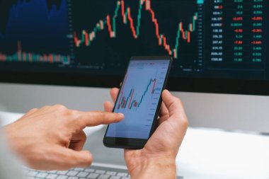 Akıllı borsa yatırımcıları ekranda akıllı telefon ile piyasa borsasını işaret ederek dizüstü bilgisayarın yanı sıra en yüksek dinamik yatırım oranını göstererek, modern işyerindeki veri planlamasına odaklanıyorlar. Bireysel.