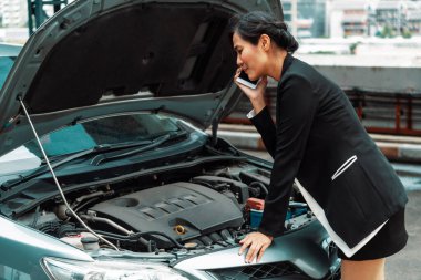 Arabası arızalı genç bir iş kadını yol yardımı için cep telefonu kullanıyor. Seyahat ve ulaşım aracı sorunu. uds