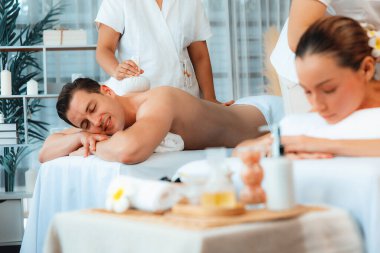 Sıcak bitkisel top spa masaj vücut tedavisi, masör nazikçe bitki torbasını çift müşteri vücuduna bastırıyor. Aromaterapi dinlenme sükuneti ve sükuneti kaplıca salonundaki atmosferi aydınlatıyor. Sessiz.