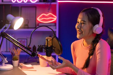 Geceleri podcast 'te olumlu konuşmalar yapan, pembe neon ışıklı modern stüdyoda sunum için dizüstü bilgisayar kullanan, gülümseyen, genç, güzel Asyalı bir etkileyiciydi. Taktik.