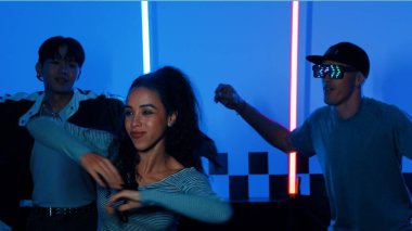 Gündelik gömlekli, gözlüklü, neon ışıkla dans eden farklı insanlar. Gece kulübünde dans ederken kameraya bakıp sokak dansı yapan çok kültürlü break dansçı. Mutluluk.