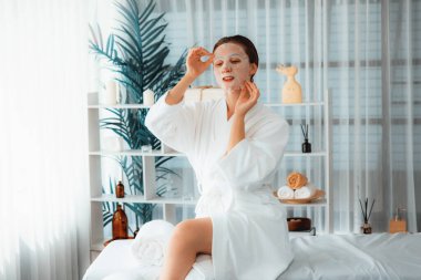 Kaplıca salonunun sakin, modern gün ışığı atmosferi, kadın müşteri poz veriyor ve yüz maskesi ile gençleştiriyor. Yüz bakımı ve güzellik kozmetolojisi prosedürü. Sessiz.