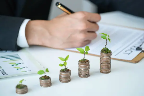 stock image Businessman with coin stack at his office as sustainable money growth investment or eco-subsidize. Green corporate promot and invest in environmental awareness. Gyre