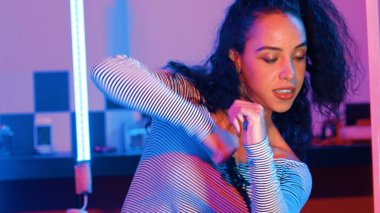 Stüdyoda mor ışıkla sokak dansı yapan İspanyol sokak dansçılarına yakın çekim. Profesyonel sanatçı şık kumaşla enerjik bir hareket sergiler. Çılgın, komik. Yarı vücut. Mutluluk.