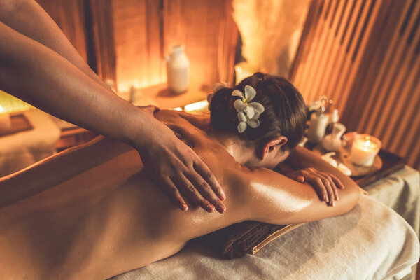 Caucasian woman customer enjoying relaxing anti-stress spa massage and pampering with beauty skin recreation leisure in warm candle lighting ambient salon spa at luxury resort or hotel. Quiescent