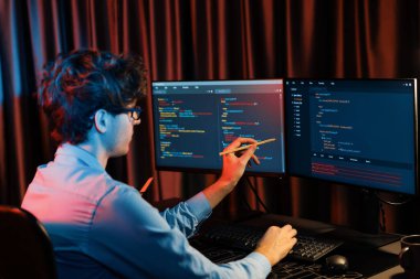 Uygulama pc ekranları ile çevrili çevrimiçi yazılım geliştirme bilgilerini yoğunlaştıran IT geliştiricisi, neon modern ofis evindeki web sitesinde yazılım için program yaratıyor. Toplayıcı.