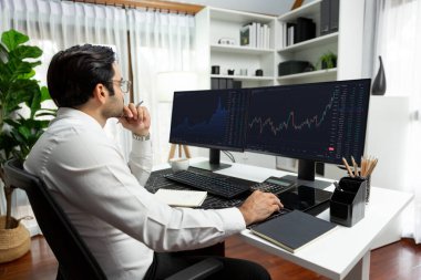 Akıllı tüccar işadamı, modern merkez ofisindeki araştırma pazarında en yüksek kârlı finansal teknolojiye yatırım yaparak bilgisayar üzerinde iki dinamik borsa yatırım ekranını analiz ediyor. Tahmin et..