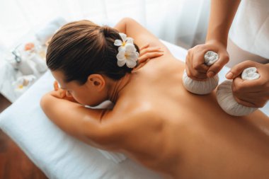 Sıcak bitkisel top spa masaj vücut tedavisi, masör kadın vücuduna nazikçe şifalı bitki torbası bastırıyor. Aromaterapi dinlenme sükuneti ve sükuneti kaplıca salonundaki atmosferi aydınlatıyor. Sessiz.