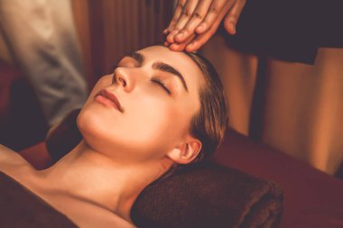 Beyaz kadın stres önleyici kafa masajı yapmaktan ve lüks otel veya otelde sıcak mum ışığında yüz güzelliği eğlencesi yapmaktan zevk alıyor. Sessiz.