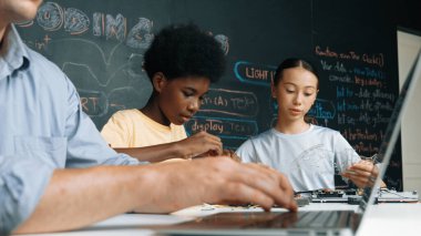 Genç öğrenci BTMM sınıfında öğretmenlik yaparken denetleyiciyi tamir ediyor. Akıllı kız elektronik alet ve karatahta kullanırken eğitmen el bilgisayarı. Öğretim.