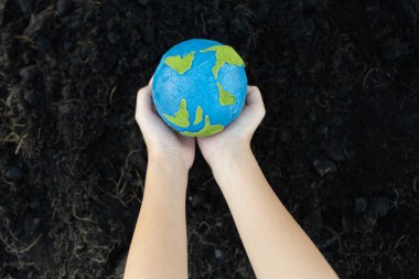Genç çocuklar Dünya gezegenini verimli toprak arka planında tutarak bu gezegeni daha parlak bir gelecek için ESG ilkesi ve çevre dostu enerjisiyle kurtarmak için Dünya günü olarak el ele tutuşuyorlar. Döngü