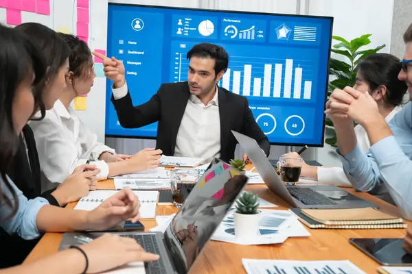 stock image Diverse group of business analyst team analyzing financial data report. Finance data analysis chart and graph dashboard show on TV screen in meeting room for strategic marketing planning. Habiliment