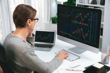 Bilgisayar ve dizüstü bilgisayarı kullanarak, çalışma masasındaki dinamik artırılmış borsa grafiğinin en yüksek kar değerini araştıran bir tüccar, modern ofisteki ekrandaki döviz kuru değerini analiz ediyor. Bireysel.