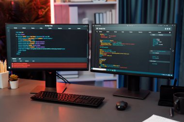 Bilgisayardaki programlama kodu masaüstü çalışma masasındaki iki ekranda akıllı web sitesi geliştirme kodlayıcı sisteminin neon ışık odasında veri teknolojisi çalıştırdığını gösteriyor. İnfobahn.