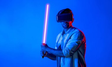 Kafkasyalı bir adam VR cam takıyor ve hareket eden el kol kılıcını tutuyor. Oyuncu, gelecekteki sanal gerçeklik kulaklığını ya da gelecekteki yenilikleri kullanarak meta dünyaya giriyor ya da aksiyon oyunu oynuyor. Sapma.