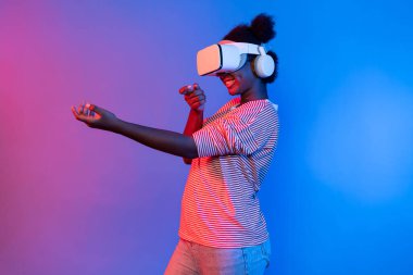 VR kullanan Afrikalı bir oyuncuyu avlamak, meta-evrende silah ateşleme oyunu oynamak, mavi neon ışığını izole etmek, zafer hayvanı avlamak, fütüristik teknoloji hologramı sanal gerçekliği. Entrika.