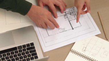 Akıllı mimar ve akıllı mühendisin dizüstü bilgisayarlı videosu mimarlık bürosundaki inşaat isabet planı hakkında tartışıyorlar. Eline odaklan. - Yakın çekim. Tanımlama.