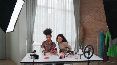 İki kadın nüfuzlu kişi canlı yayında video görüntülerini çekiyor. Makyaj çok önemli sosyal medya veya blog. Kozmetik stüdyosu ışıklandırmalı mutlu genç kız çevrimiçi pazarlama oturumu yayını için..