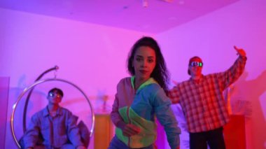 İspanyol hipster renkli kıyafetler giyer ve serbest stil müziğe el sallar. Profesyonel break dansçı neon ışıklarıyla ve modern stüdyo arkadaşlarıyla coşkuyla dans ediyor. Mutluluk.