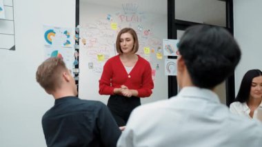 Yetenekli genç ve güzel iş kadını, yaratıcı iş toplantısında yakışıklı yönetici dinlerken zihin haritalama ve istatistiksel grafik kullanarak pazarlama fikrini kendine güvenle sunuyor. Tertemiz..