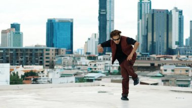 Profesyonel Asyalı break dansçı B çocuk dansı yaparken çatıda çok kültürlü arkadaşlar var. Genç modern dans grubu hip hop hareketi yapıyor. Tarz, moda, aksiyon. Açık hava sporu 2024. Hiphop.