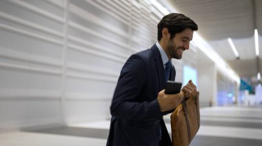 Mutlu iş adamı beyaz koridorda yürürken başarılı projesini kutluyor. Proje yöneticisi terfi almak, yeni bir pozisyon almak veya satışları artırmak hakkında iyi haberler alıyor.