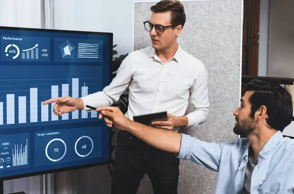 Stock image Presentation in office or meeting room with analyst team utilizing BI Fintech to analyze financial data. Businesspeople analyzing BI dashboard power display on TV screen for strategic planning.Prudent