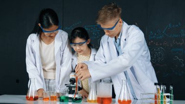 Zeki kız deney yapmak için heyecanlanan çeşitli öğrenciler iken beher kabına renkli solüsyon döker. Profesyonel bilim adamı kimyasal teoriyle kara tahtada deney yapmaya hazırlanıyor. Öğretim.