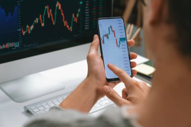 Akıllı borsa yatırımcıları ekranda akıllı telefon ile piyasa borsasını işaret ederek dizüstü bilgisayarın yanı sıra en yüksek dinamik yatırım oranını göstererek, modern işyerindeki veri planlamasına odaklanıyorlar. Bireysel.