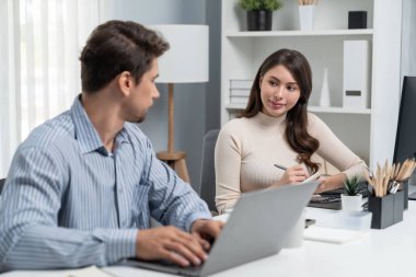 Akıllı yönetici dizüstü bilgisayarla yazarken iş analizi raporu için veri araştırma projesini modern ofis saatinde masa başında sorarak kadın iş arkadaşıyla konuşuyor. Varsayım.