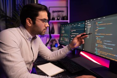 İki pc ekranda veri yazılım geliştirme üzerine çalışan akıllı bilişim geliştiricisi, neon ışıklı siber ofiste güncellenmiş uygulama programı güncellenmiş web sitesi sayfası sistemi yaratıyor. Tahmin et..