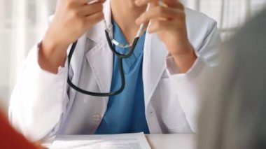 Hasta klinikte ya da hastane ofisinde doktor randevusuna gidiyor. Hastaların nabzını steteskopla kontrol edip risk faktörünü belirleyen doktor semptomları inceliyor. Ağır çekim. Katı.