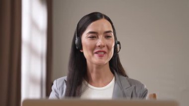 Kadın çağrı merkezi operatörü ya da müşteri hizmetleri çalışanı, müşteriye yardım etmek için kulaklıkla konuşurken çalışma alanı üzerinde çalışıyor. Profesyonel modern iş hizmeti. Blithe