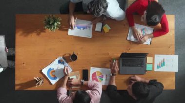 Yöneticinin yukarıdan aşağı görüntüsü tablet görüntüsünü artırıyor ve toplantı masasına yerleştiriliyor. Çeşitli iş adamlarından oluşan bir grup, toplantı odasındaki başarılı ürünü kutlamak için el çırpıyor..