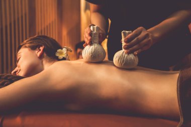 Sıcak bitkisel top spa masaj vücut tedavisi, masör nazikçe bitki torbasını çift müşteri vücuduna bastırıyor. Aromaterapi salonda mumların sıcacık ışığında dinlenme sükuneti. Sessiz.