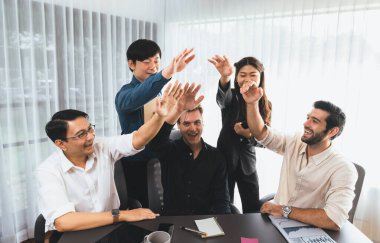 Çeşitli ofis çalışanlarından oluşan bir grup, ofis odasında el ele vererek iş sinerjisini ve iş yerindeki güçlü verimli takım çalışmasını sembolize ediyor. İş çalışanları arasındaki işbirliği ve birlik. Tedbirli
