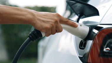 Modern çevre dostu adam EV şarj istasyonundan elektrikli aracı şarj ediyor. EV araba teknolojisi ev sakinleri için gelecekte çevresel sürdürülebilirlik için kullanılıyor. Eşzamanlama